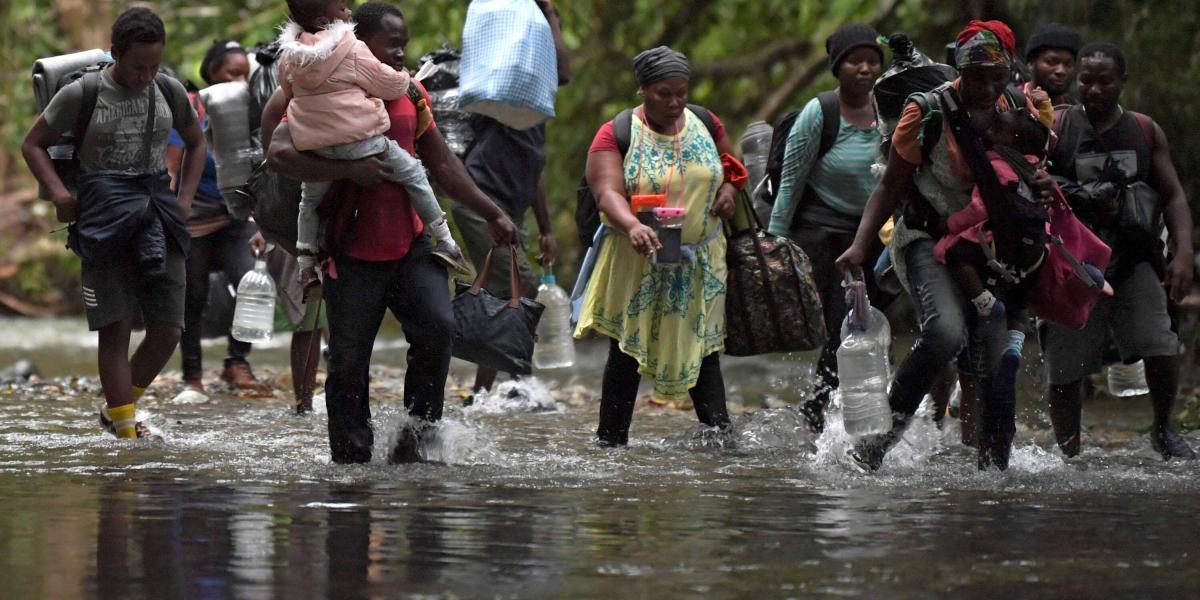 Un grupo de haitianos cruza un río en la zona 
del Darién colombiano. Van con niños, personas mayores y equipaje.