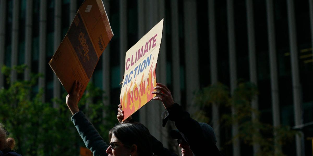 Los manifestantes sostienen carteles durante la Marcha por la Justicia Climática desde Times Square, mientras en la COP26 llegan a un acuerdo.