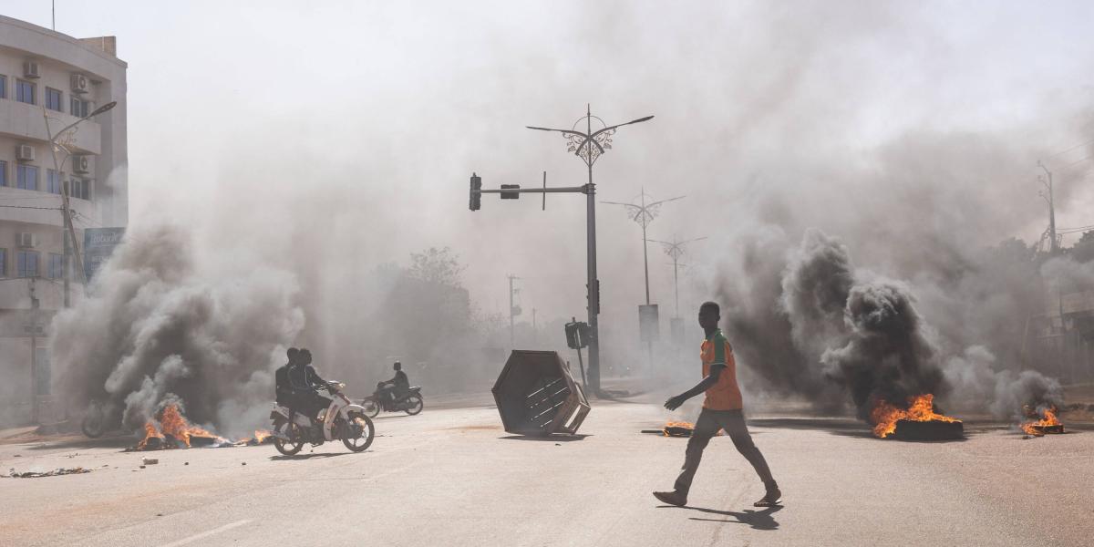 Un hombre cruza barricadas en llamas en las avenidas centrales de Uagadugú, donde un grupo de jóvenes manifestantes que apoyaban el papel del ejército protestaron contra el presidente Marc Christian Kabore el 23 de enero de 2022.