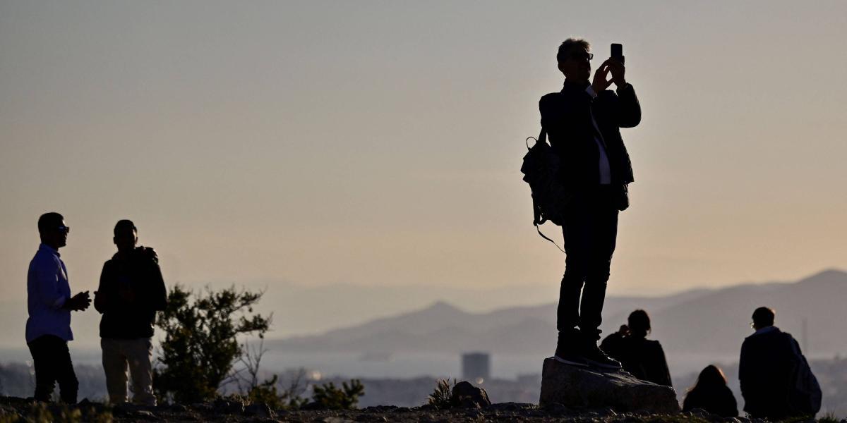 Turistas toman fotografías desde una colina en Atenas (Grecia), un destino que espera seguir u pronta recuperación.
