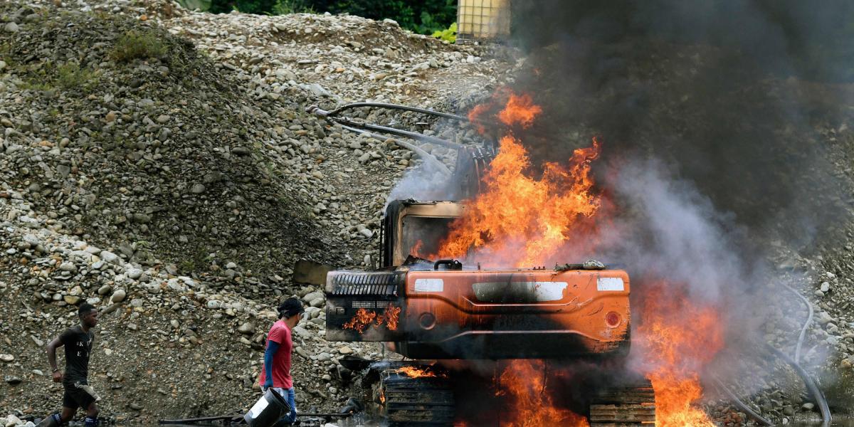 Habitantes de la zona que trabajan en la minería ilegal intentan apagar el fuego de la maquinaria.