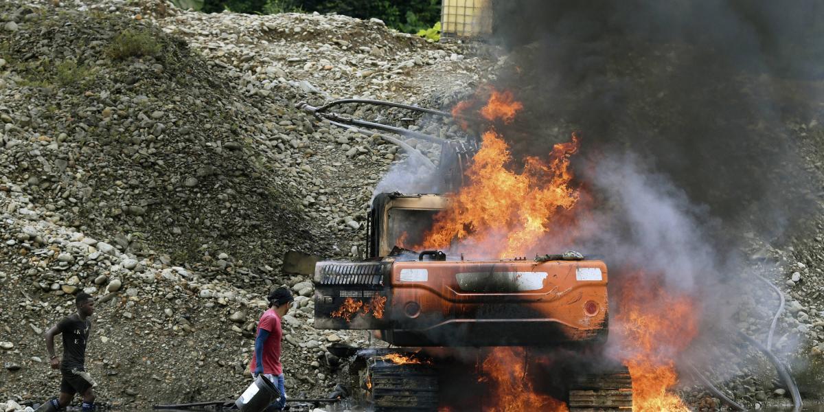 Habitantes de la zona que trabajan en la minería ilegal intentan apagar el fuego de la maquinaria pesada.
