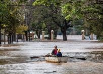 -Una mujer acompañada de un niño conduce una embarcación por una calle inundada este lunes en Concordia (Argentina).