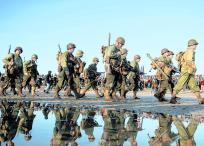 Entusiastas vestidos con atuendos militares de la Segunda Guerra Mundial del ejército de EE. UU. desfilan a lo largo de Utah Beach.
