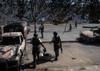Policías custodian este martes los exteriores comisaría de Carrefour Aéroport, que fue incendiada la noche de ayer por miembros de pandillas, en Puerto Príncipe (Haití).