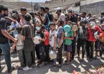 Hombres, mujeres y niÃ±os hacen cola para recibir raciones de comida en una cocina pÃºblica de Deir el-Balah, en el centro de Gaza.