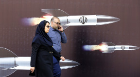 Iraníes pasan junto a una enorme pancarta antiisraelí con imágenes de misiles, en Teherán.