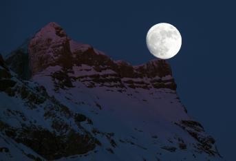 La luna 'posó' sobre las montañas en Gryon al oeste de Suiza, este primero de enero de 2018.