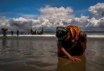 Una mujer refugiada rohingya agotada toca la orilla luego de cruzar la frontera entre Bangladesh y Myanmar en barco por la Bahía de Bengala, en Shah Porir Dwip, Bangladesh.