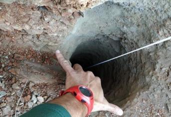 Un guardia civil señala el orificio, de apenas 30 centímetros de ancho, del pozo de más de 100 metros de profundidad por el que cayó un niño de dos años en una finca privada de la localidad malagueña de Totalán.