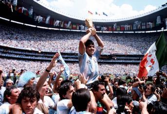 Un momento icónico de la carrera de Maradona: cargado a hombros tras la final de la Copa del Mundo en el Azteca en 1986. En medio de un tumulto de fanáticos, periodistas y fotógrafos, se puede ver cómo los espectadores y los hinchas tiran su camiseta y hacen todo lo posible por tocarlo; todo el mundo quiere un pedazo de Diego.
