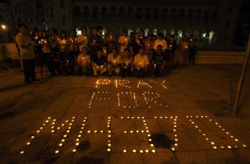 Varias personas posan frente a un conjunto de velas que conforman la frase "Rezar por MH370", durante una vigilia en memoria de las 239 personas que viajaban a bordo del avión de Malaysia Airlines.