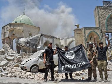 Un miembro de las Fuerzas Iraquíes levanta el gesto de la victoria mientras otros sostienen la bandera negra del grupo Estado Islámico,enlas ruinas de la mezquita de Al-Nuri en la Ciudad Vieja de Mosul.