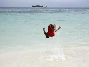 Un niño hace una acrobacia en la isla de San Andrés. Al fondo está la isla de Johnny Cay.