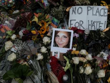 Fotografía de Heather Heyer, víctima del atentado en Charlottesville, Virginia, en medio de flores y letreros de repudio a la violencia.