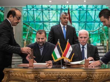 El miembro palestino del comité central de Al Fatah, Azam al-Ahmed, y el líder del movimiento islamista Hamás, Saleh al Aruri, firman un acuerdo ante la mirada del ministro egipcio de Inteligencia, Khalid Fawzi.