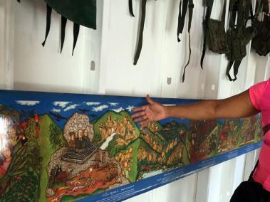 La exguerrillera Luz Dary Díaz enseña el lienzo que se encuentra al interior de la que será la Casa de la Memoria. La pintura retrata la lucha campesina.
