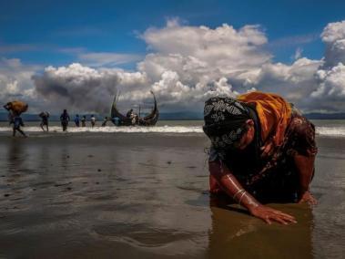 Una mujer refugiada rohingya agotada toca la orilla luego de cruzar la frontera entre Bangladesh y Myanmar en barco por la Bahía de Bengala, en Shah Porir Dwip, Bangladesh.