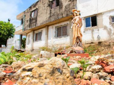 Sobre escombros y maleza quedó en pie una escultura de la Virgen, amputada en uno de sus brazos, a la cual le rezan los familiares de las víctimas.