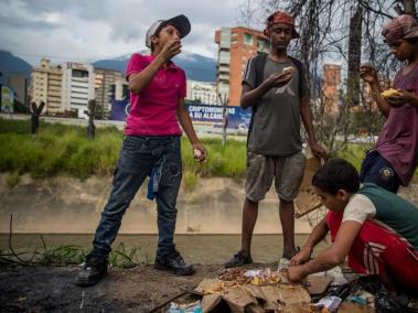 Un grupo de niños busca comida entre bolsas de basura que obtuvieron en una panadería de Caracas, capital de Venezuela.