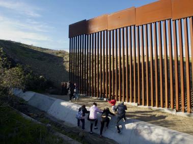 Migrantes hondureños tratando de cruzar el muro en la frontera sur estadounidense con Tijuana (México).