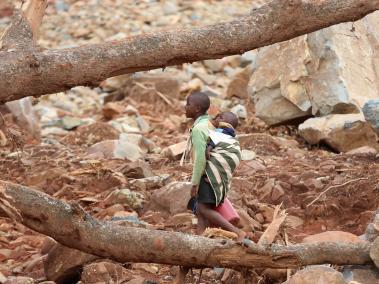 Un niño con un bebé en su espalda camina a través de escombros después del ciclón Idai en Ngangu, Chimanimani, Zimbabwe.