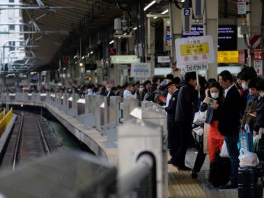 Cientos de pasajeros esperan en fila tomar el tren en la estación central de Tokio.