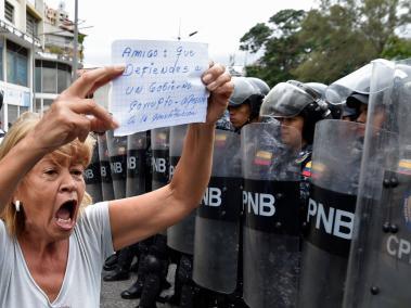 Una manifestante acude a las marchas convocadas por la oposición en Venezuela. El cartel dice: "Amigo: que defiendes a un gobierno corrupto. Apégate a la constitución (sic)".