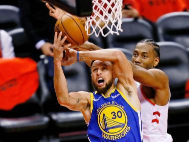 Stephen Curry (30), de Warriors, disputa el balón con Kawhi Leonard (2), de Raptors, en una de las acciones del juego.