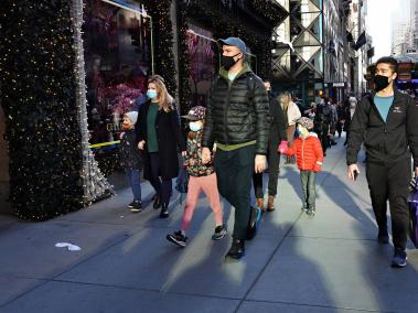 Personas con máscaras protectoras caminan por las ventanas navideñas en Saks Fifth Avenue el 29 de noviembre de 2020 en la ciudad de Nueva York.