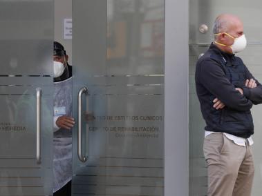 Fotografía de archivo fechada el 8 de septiembre de 2020 que muestra a un hombre que espera a la entrada del Centro de Estudios Clínicos de la Universidad Cayetano Heredia, mientras un trabajador de la salud se asoma, en Lima (Perú).