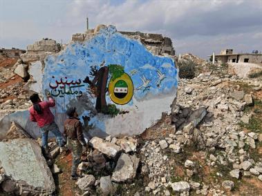 Sirios pintan un mural sobre los restos de un edificio en la ciudad de Binnish, en la provincia noroccidental de Idlib, en Siria, el 11 de marzo de 2021, marcando los 10 años de la guerra siria.