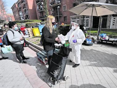 Gente recibiendo alimentos en un barrio de Madrid por parte de un grupo de ayuda humanitaria.
