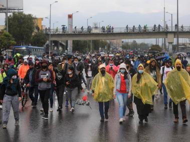 Un grupo de personas camina sobre la av. Américas. En este corredor ha habido enfrentamientos entre miembros del Esmad y un grupo de manifestantes.