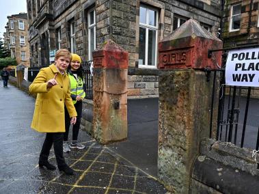 La Primer Ministro de Escocia y líder del Partido Nacional Escocés (SNP), Nicola Sturgeon (L) y la candidata Roza Salih (2L) hacen un gesto en el colegio electoral de Annette Street en Glasgow, Escocia, el 6 de mayo de 2021