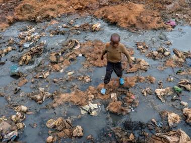 Un niño atraviesa un drenaje contaminado en Kenia. Los efectos climáticos amenazan el agua y la seguridad alimentaria mundial.