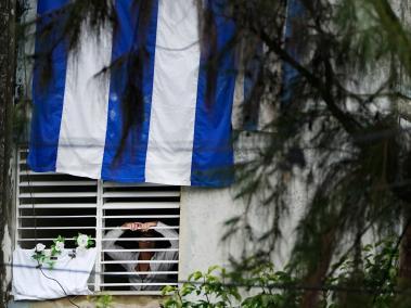 Yunior García Aguilera, dramaturgo y uno de los fundadores del grupo Archipiélago muestra una flor blanca a través de una ventana de su casa en La Habana, Cuba.