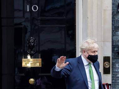 El primer ministro británico, Boris Johnson, que se cubre la cara para ayudar a mitigar la propagación del coronavirus, saluda cuando sale de 10 Downing Street en el centro de Londres el 19 de enero de 2022 para participar en la sesión semanal de Preguntas al Primer Ministro (PMQ) en la casa de los Comunes.