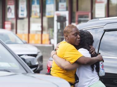 Dos personas se abrazan cerca de la escena de un tiroteo masivo en la tienda e comestibles Tops Friendly Market en Buffalo, Nueva York.