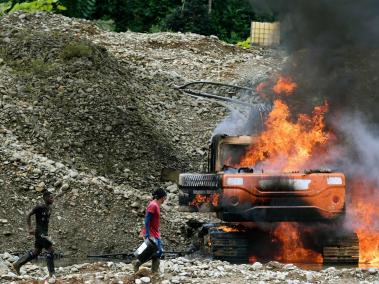 Habitantes de la zona que trabajan en la minería ilegal intentan apagar el fuego de la maquinaria.
