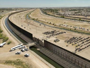 Cientos de migrantes mientras esperan junto al muro fronterizo en El Paso, Texas (EE.UU).