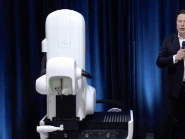 El controvertido magnate Elon Musk, junto al robot quirúrgico que sería el encargado de insertar el implante a los humanos.