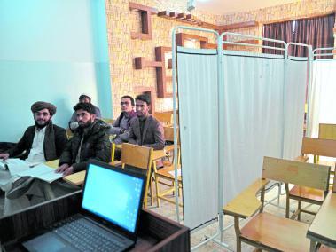 Estudiantes hombres asisten a clase en un salón separado por una cortina, donde antes se le impartía clases a las mujeres.