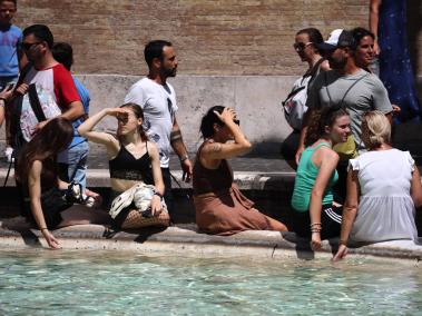 Transeúntes en Italia soportan la ola de calor.