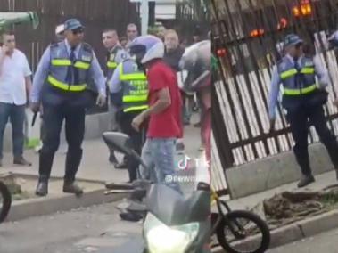 El agente de tránsito sostiene el arma que aparentemente le quitó al motociclista.