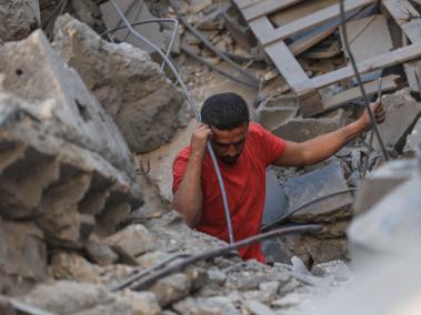 Palestinos buscan supervivientes entre los escombros de un edificio tras un bombardeo israelí en Rafah.