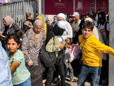Gente camina por una puerta para ingresar al cruce fronterizo de Rafah con Egipto.