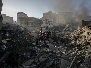 Palestinos buscan cadáveres y supervivientes entre los escombros en una zona destruida tras los ataques aéreos israelíes en la ciudad de Gaza, 25 de octubre de 2023. •