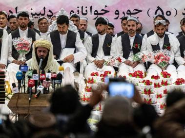 Novios afganos observan durante una ceremonia de boda masiva en un salón de bodas en Kabul.