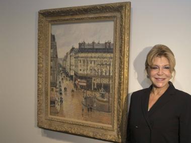 La baronesa Carmen Thyssen, junto al cuadro Rue Saint Honoré por la tarde, de Camille Pissarro.